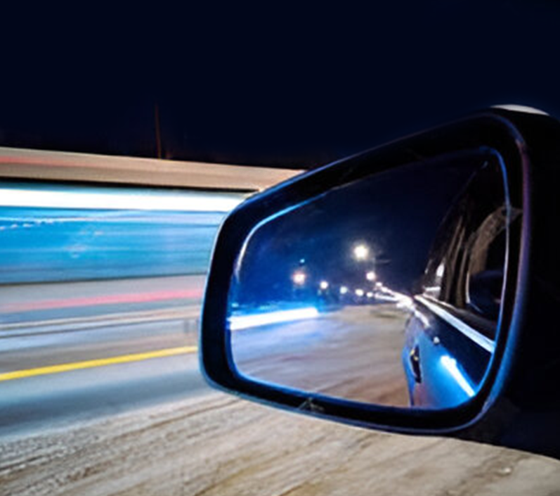 A car 's side view mirror reflecting the street lights.