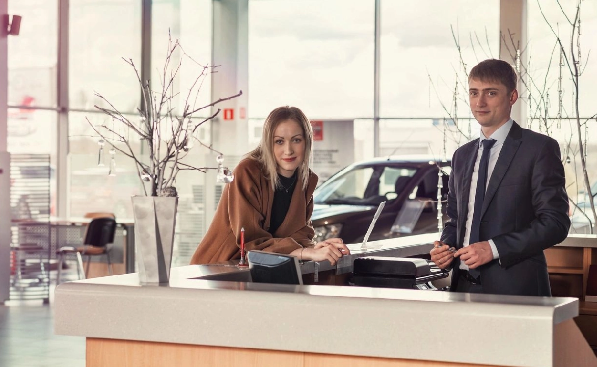 A man and woman are standing in front of the car.