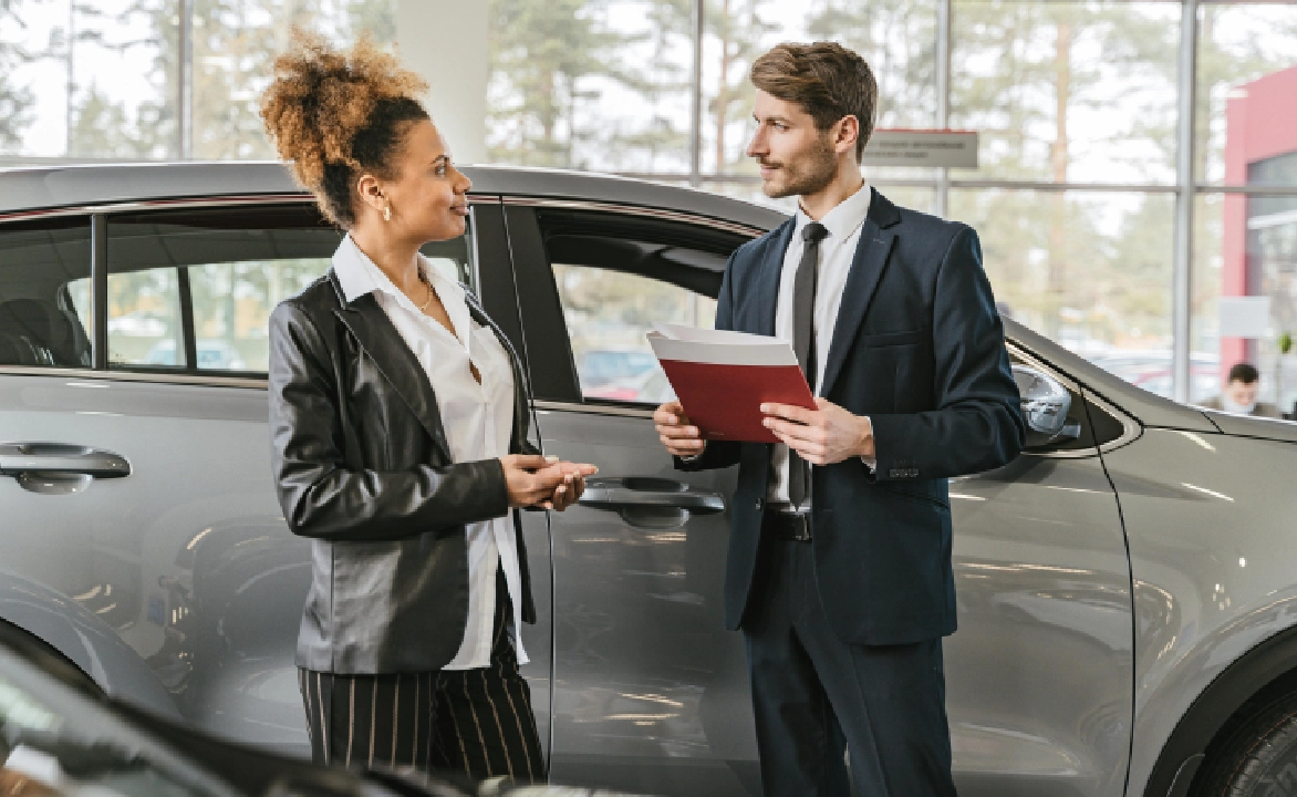 A man and woman are talking in front of a car.